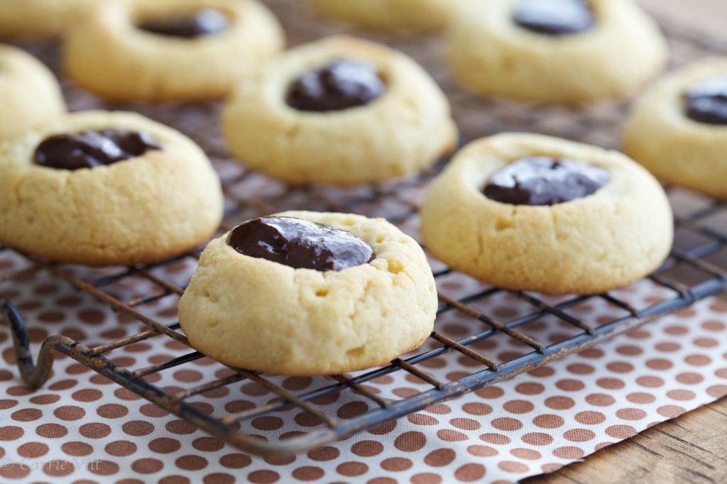 Image shows rows of thumbprint cookies on a black cooling rack