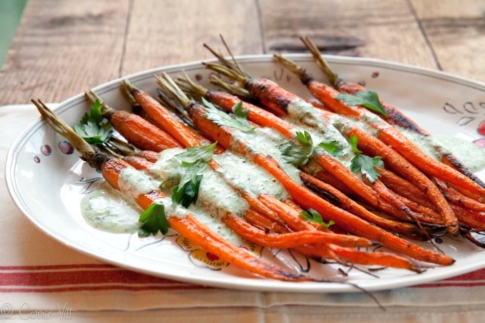 Roasted Carrots with Parsley-Yogurt Dressing - The baby carrots are tossed in ghee, roasted and then served with a savory yogurt sauce with fresh parsley and spices. A beautiful addition to a festive family meal!