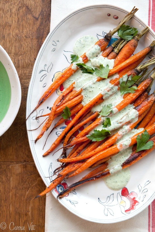Roasted Carrots with Parsley-Yogurt Dressing - The baby carrots are tossed in ghee, roasted and then served with a savory yogurt sauce with fresh parsley and spices. A beautiful addition to a festive family meal!